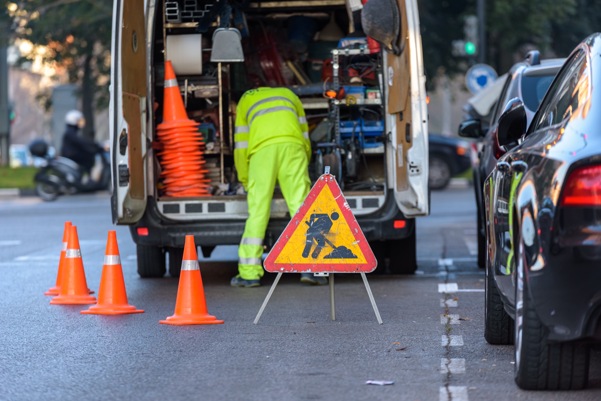 Worker inside his van, loaded with tools, protected from traffic with cones